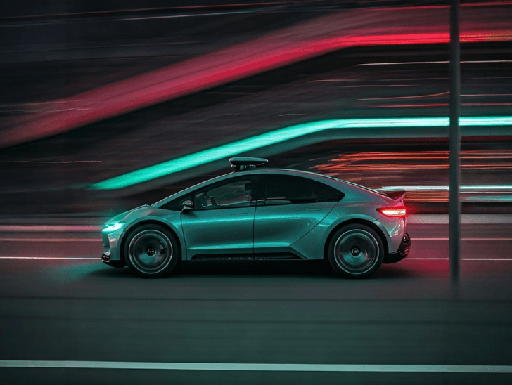 Autonomous vehicle moving through neon city light trails